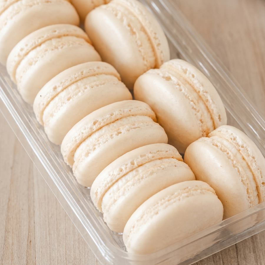 French macarons arranged neatly on a white tray with smooth shells and creamy filling.